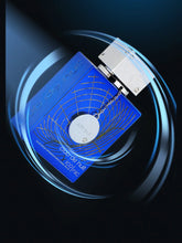 A blue Armaf Club De Nuit Iconic Citrus Woody Perfume for Men by Showlu Well Nation Store, featuring a silver cap, circular tag, gold accents, and elegant swirls, set against a dark abstract background with light blue streaks.