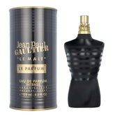 A black and gold cylindrical container stands beside a black, torso-shaped perfume bottle with gold accents, showcasing Jean Paul Gaultier Le Male Cologne 125ml by Showlu Well Nation Store.