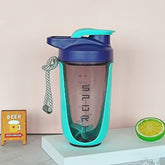 A blue and turquoise 590 ml/20 oz Premium Protein Powder Shaker (leak-proof Tritan, BPA-free, plastic ball) with a handle and markings stands on white; made in China, beside a mini BEER sign (left) and half lime slice (right). Brand: none.