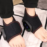 A person wears the Showlu Well Nation Store Portable Electric Wireless Vibration Heating Foot Massager, featuring black wraps with red stitching, side control panels, and secure closures around the feet and ankles.