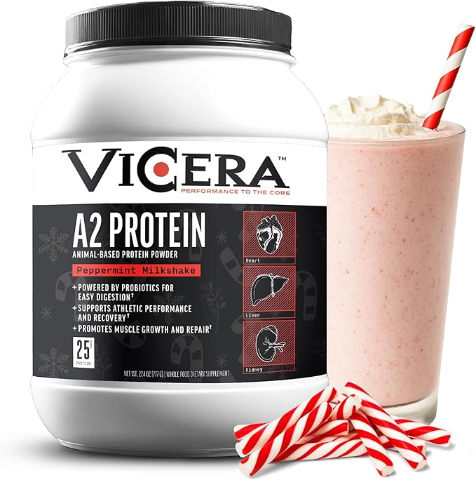A tub of A2 Protein Powder, Peppermint Milkshake flavor (25g protein/serving, organic A2/A2 whey casein with probiotics and Celtic sea salt), sits next to a pink milkshake with whipped cream, a striped straw, and peppermint candies.