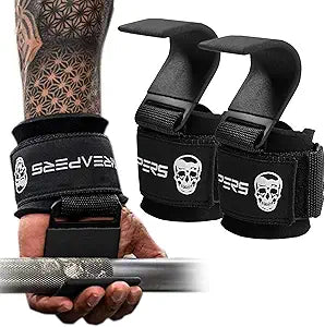 A tattooed arm grips a barbell using black Gymreapers Weight Lifting Hooks with a skull logo and metal hook; the matching pair rests nearby.