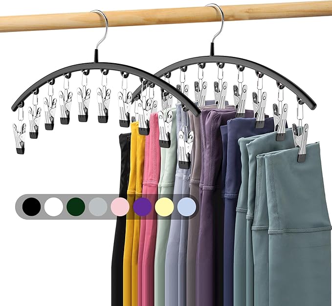 Two black metal Legging Organizers for Closet, each with 10 rubber-coated clips, hang on a wooden rod holding colorful leggings. Seven swatches below show color options for these space-saving yoga pants hangers (2 pack) that hold up to 20 leggings.