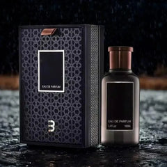 A sleek black 100ML Eau De Parfum For Men (3.4 oz) stands beside its sealed high-end gift box with a metallic 3, both on a wet surface with blurred raindrops, evoking a fresh, woody scent and premium packaging.
