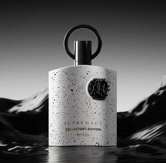 A white, speckled bottle labeled "Afnan Supremacy Collector's Edition for Men Eau De Parfum, 3.4 Fl. Oz" stands upright with a metallic circular cap against a wavy black background.