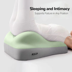 A person in white leggings rests their legs on the Multi-Functional Ergonomic Bed Pillow, a light green and gray memory foam wedge cushion. Text above reads: Sleeping and Intimacy - Supports Posture in Any Position.