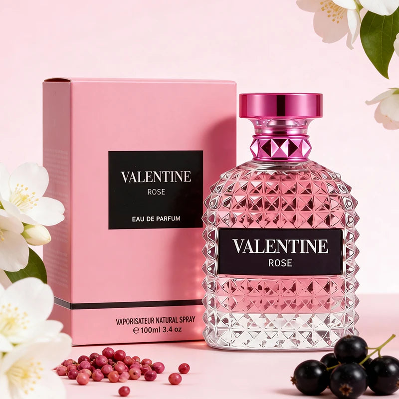 A pink glass bottle labeled “3.4 Fl Oz Men's and Women's Eau De Parfum” with a matching pink box sits on a light pink background. Mandarin orange, orange blossom, and bergamot notes hint at the unisex fragrance—ideal as a Christmas gift.