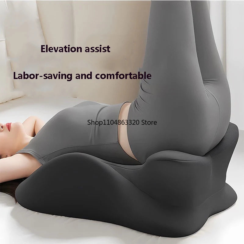 A person uses the Memory Foam Pillow Ergonomic Support, a black wedge-shaped cushion, to elevate their legs while lying down. Text on the image reads, “Elevation assist” and “Labor-saving and comfortable.”.