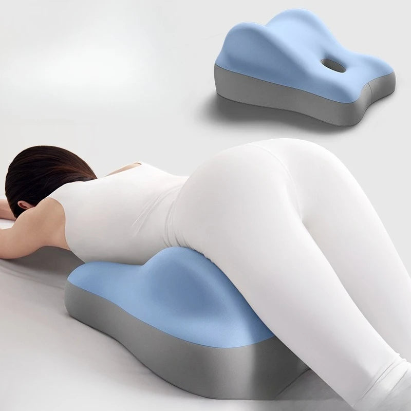 A person in white lies face down on the Multi-Functional Ergonomic Bed Pillow, a blue and gray memory foam wedge-shaped cushion that supports the hips and pelvis. An additional image displays its contoured shape and center hole.