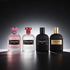 Four 3.4 Fl Oz Eau De Parfum bottles, two clear and two matte black, stand in a row. Featuring Mandarin Orange, Orange Blossom & Bergamot scents, these unisex fragrances are perfect Christmas gifts and shine on the reflective surface.
