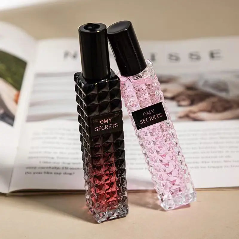 Two textured glass bottles of Miss Adventure Donna Perfume, one black-to-red and one light pink, sit on an open magazine, showcasing a lasting fresh floral fruity scent with rose and jasmine notes—perfect for daytime wear.