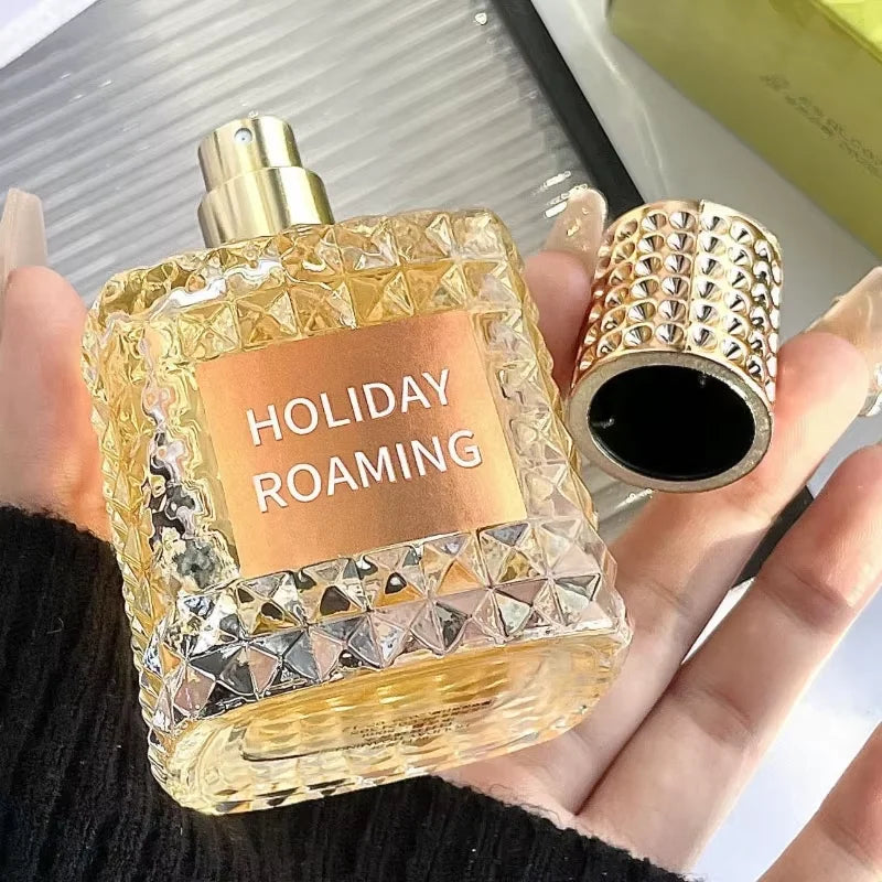 A hand holds the Rivet Series Fresh Perfume, a square bottle of golden liquid with its cap removed. This elegant EDT blends woody, fruity, and floral notes with bergamot for a high-quality, long-lasting fragrance for ladies.
