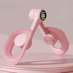 The Non-Slip Comfortable Pelvic Floor Muscle Trainer, a pink leg and thigh exerciser with curved handles and a small display, is shown on a matching surface, ideal for postpartum recovery, leg and butt training against a soft pink backdrop.