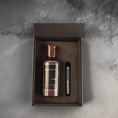 A metallic bottle of Bharara King Eau De Parfum 100ml for men and a small labeled vial sit in a black gift box on a gray textured surface, highlighting the modern luxury of this long-lasting 2025 cologne.
