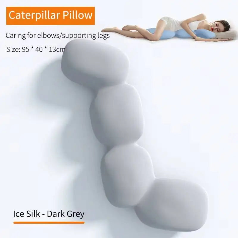 A woman rests on her side with the Memory Foam Hold In Bed Sleeping Body Pillow, a long, segmented, dark grey cushion. Its memory foam offers elbow and leg comfort, and the removable ice silk cover is washable for easy care.