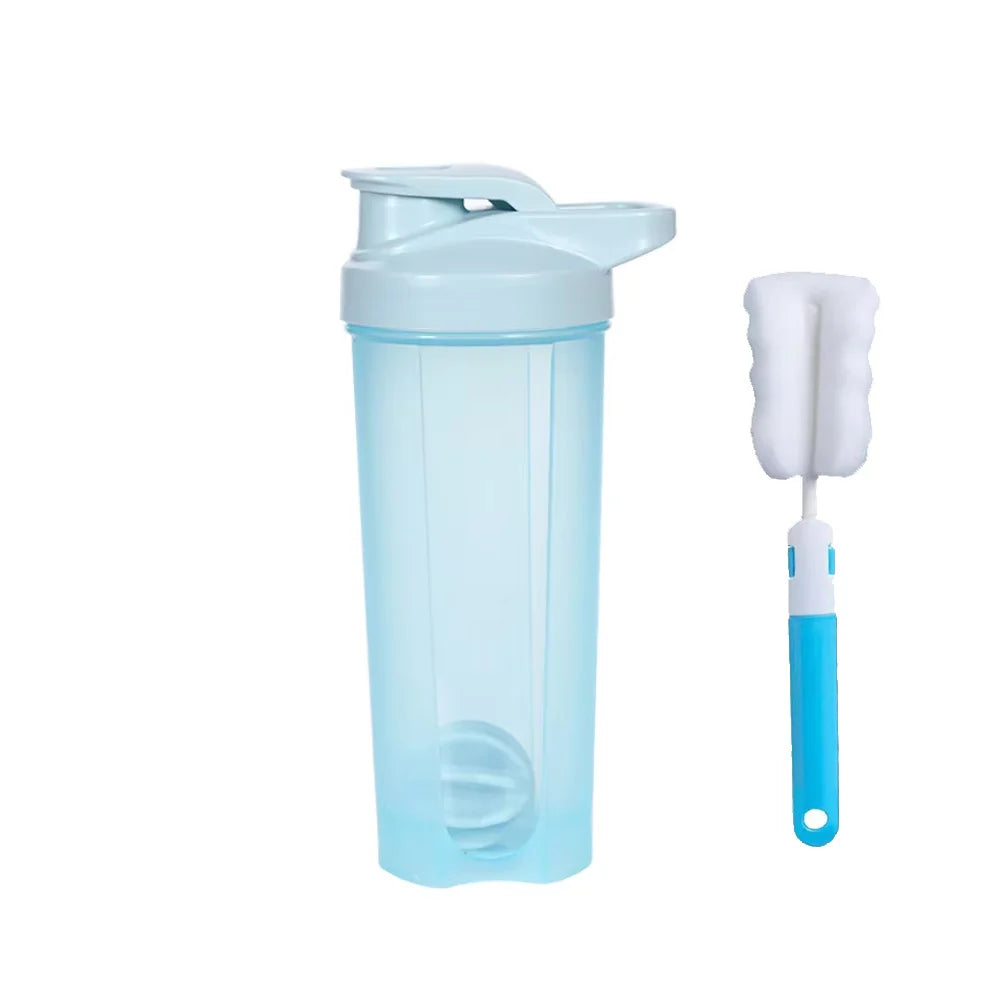 A light blue 28 oz Shaker Bottle for Protein Shakes with a matching lid and blender ball sits beside a blue and white chemical-free cleaning brush with a foam head, both displayed on a white background.