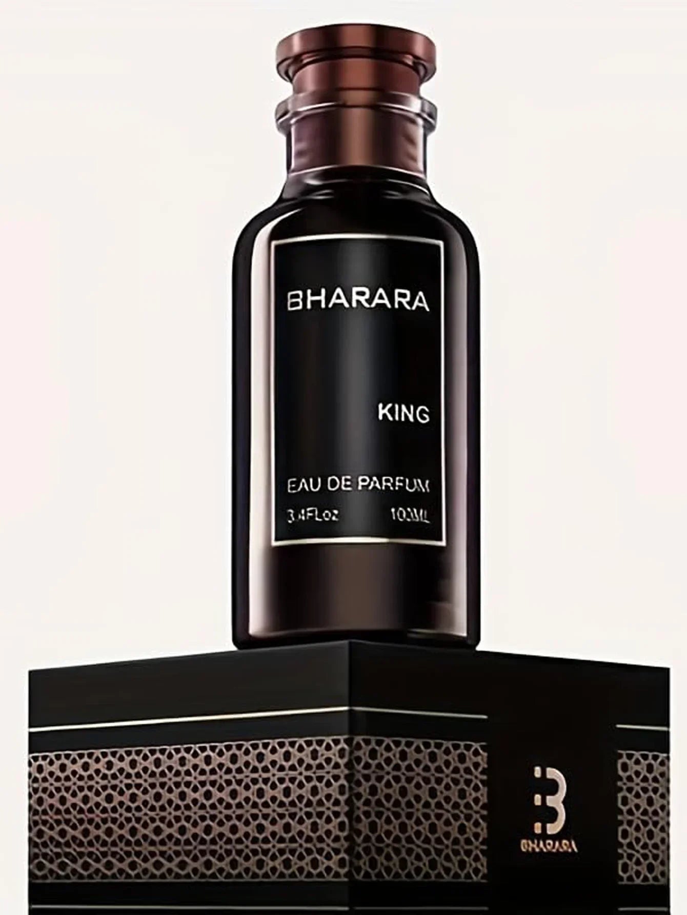 A dark brown bottle labeled Bharara King EDP 3.4oz, a bold woody amber men’s cologne with a long-lasting luxury scent, stands on a black and gold patterned box featuring a stylized B logo against a plain light background.