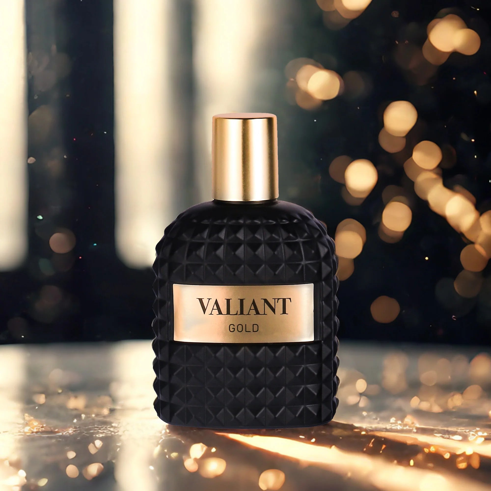 A black, textured 3.4 Fl Oz Eau De Parfum bottle labeled VALIANT GOLD with a gold cap sits on a reflective surface, radiating a unisex Mandarin Orange, Orange Blossom & Bergamot scent—perfect for Christmas gifts.