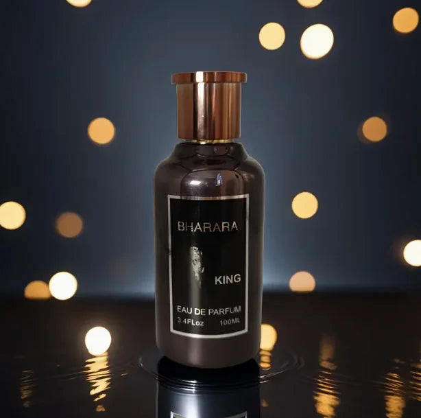 A 100ml bottle of Bharara King Eau De Parfum for men, with a gold cap and label, stands upright on a reflective surface against warm bokeh lights, highlighting its sleek, luxurious design popular in Mainland China.
