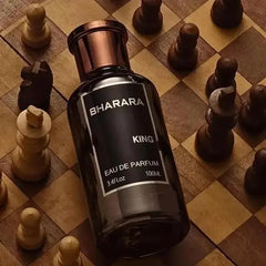 A bottle of Bharara King Men's Eau de Parfum 3.4oz (100ml), a long-lasting, formaldehyde-free citrus & musk fragrance, rests on a wooden chessboard among chess pieces, with its label clearly visible.