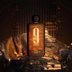A black and orange Afnan 9 PM Elixir Unisex Extrait de Parfum 3.4 Fl. Oz bottle stands upright on rocky terrain, against a dramatic golden-brown backdrop with falling leaves and warm light—a striking unisex fragrance scene.