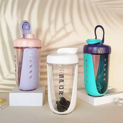 Three Premium Protein Powder Shakers (590ml, BPA-free Tritan) with mixing balls are on white platforms. The pastel purple/pink, white/gray, and teal/navy bottles from China stand before a leaf-shadowed background.
