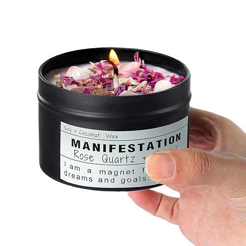 Handheld black tin Crystal Soy Candle with rose quartz crystals and dried flowers, manifestation theme.