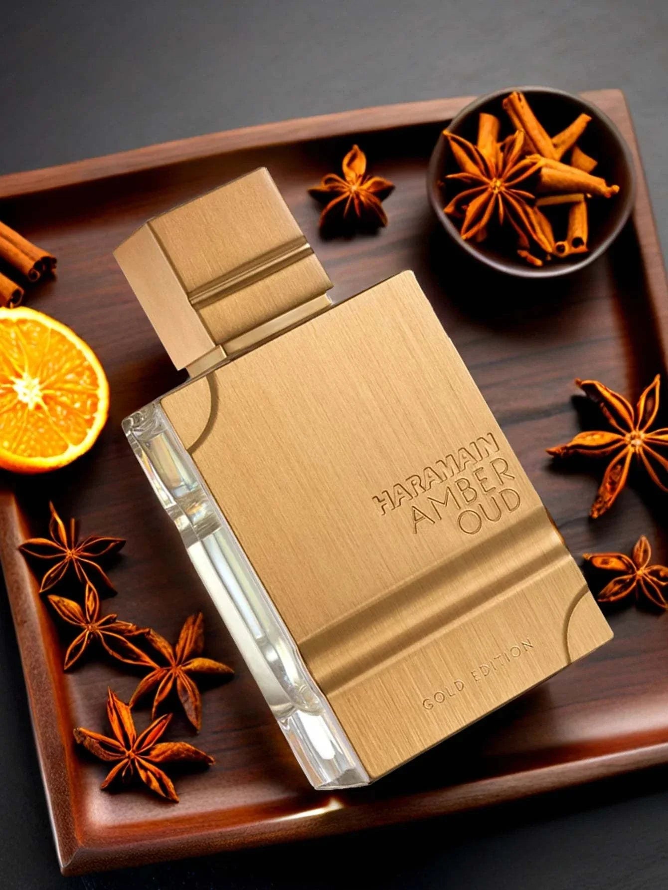 Haramain gold edition luxury amber oud perfume bottle on wooden tray with spices and orange slice